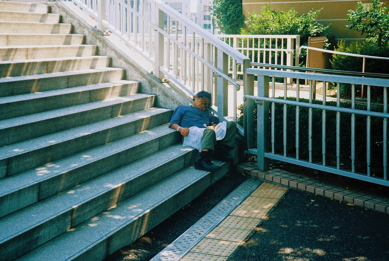 一个人坐在楼梯旁边的长椅上