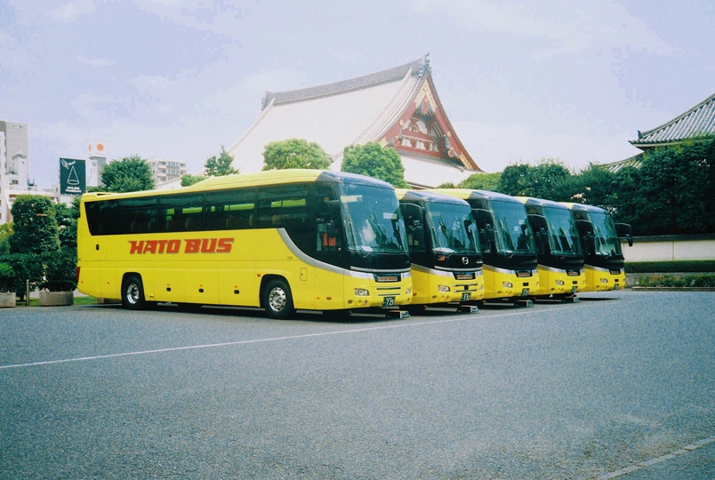 几辆公共汽车停在大型建筑物前面的停车场里。