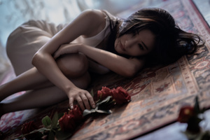 一个美丽的年轻女人躺在地毯上 地毯上放着红玫瑰