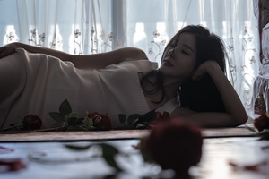 一位年轻女子躺在一间白色房间的床上 房间里地板上有玫瑰花