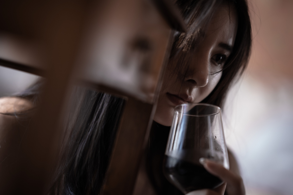 一个年轻的女人拿着一杯红酒看着镜子