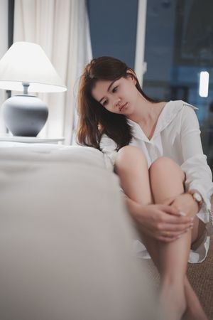一个年轻女子穿着白色衬衫坐在沙发或椅子上的一间房间