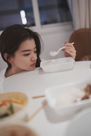 一个年轻女子坐在桌子旁吃一碗汤。