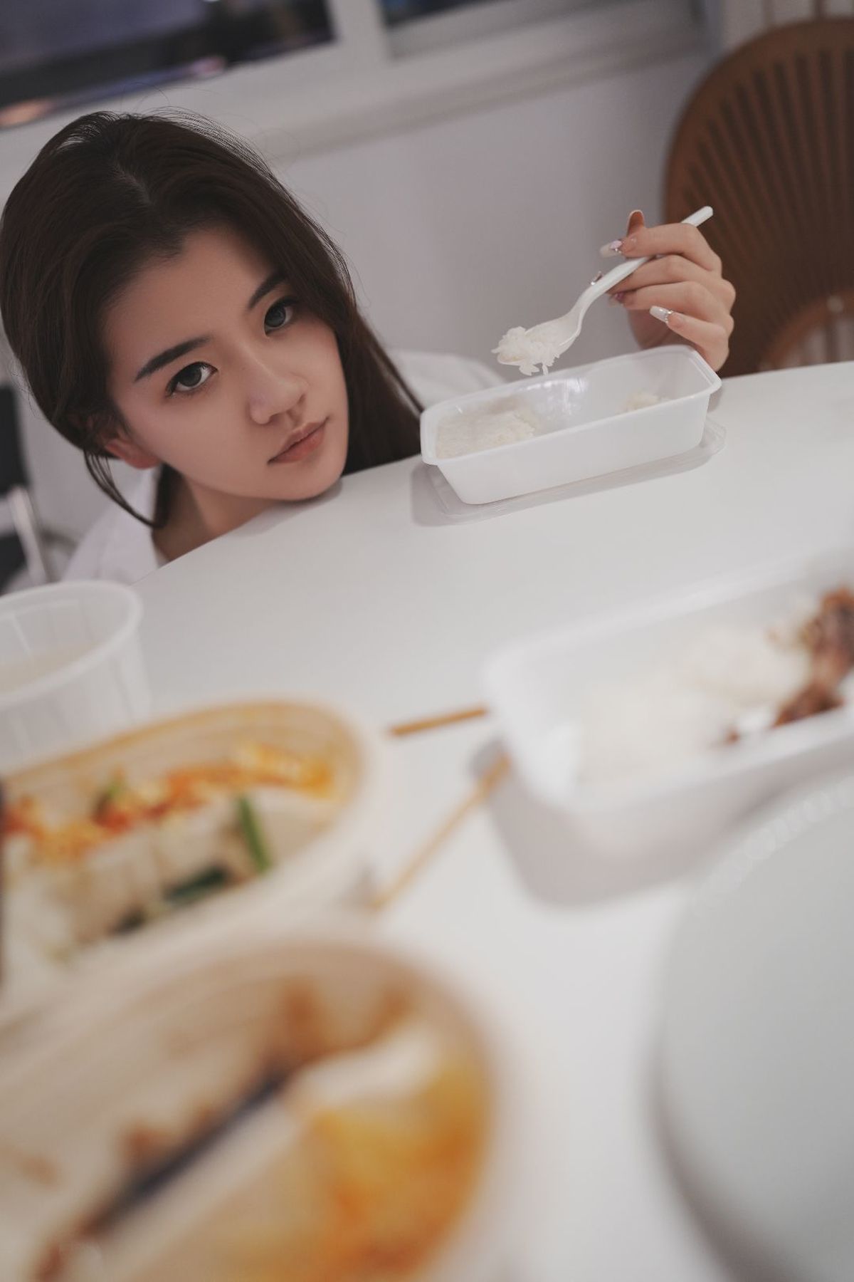 一个年轻女子坐在桌子旁吃着一碗食物