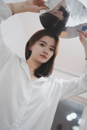 一位年轻女子穿着一件白色衬衫 正在镜子前梳理她的头发。