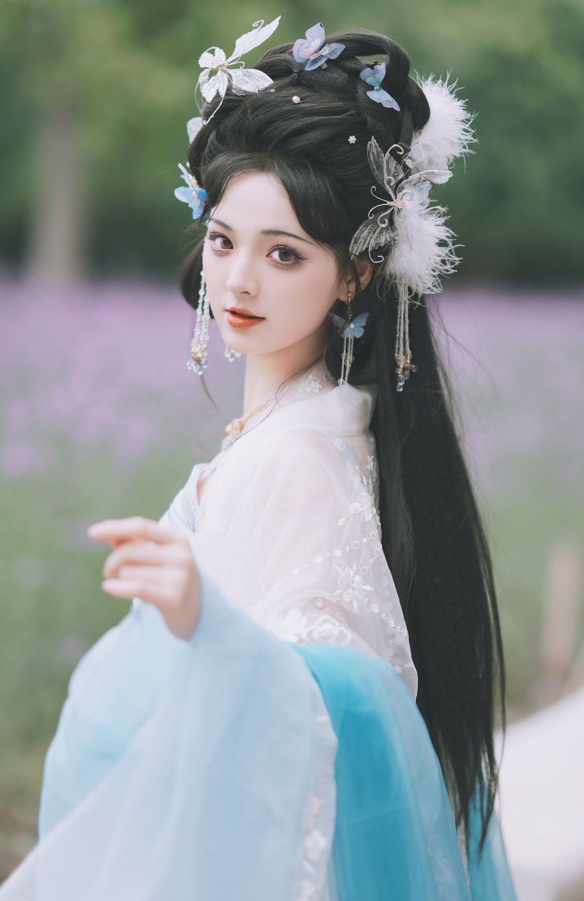 一位美丽的年轻女子 长发 身着传统蓝色连衣裙 上面有花纹。