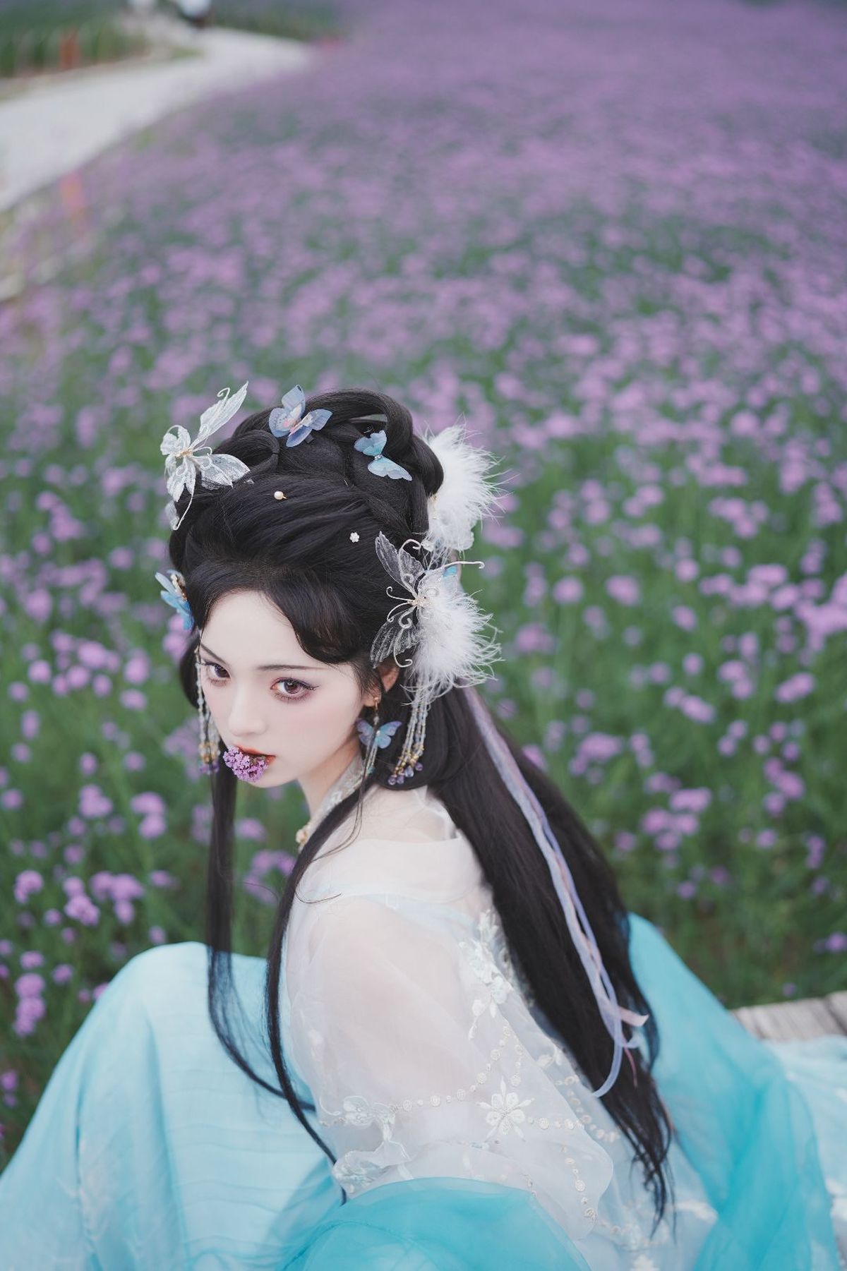 一位穿着传统裙子的美丽年轻女子 蓝发 置身于紫花丛中。