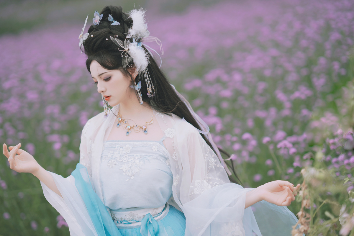 美丽的年轻女士身着传统服装坐在紫花丛中