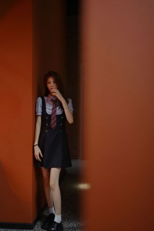 一位穿着制服的年轻女子站在一堵墙和一扇门之间的过道里。