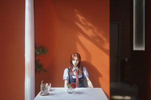 一位年轻女子坐在红墙前的白色桌子旁