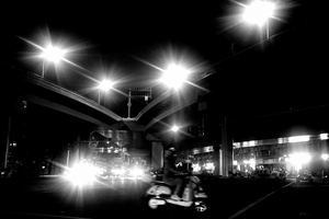 一张黑白照片 一个人在晚上骑摩托车穿过城市街道