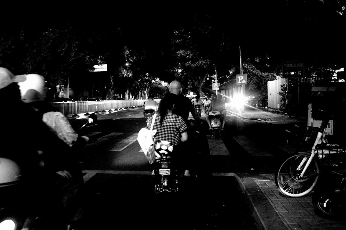 一张黑白照片 夜晚街道上骑摩托车的人们