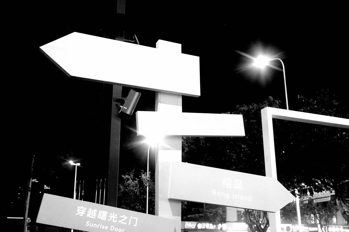 一张黑白照片 夜晚街道 白色标志 箭头指向右侧