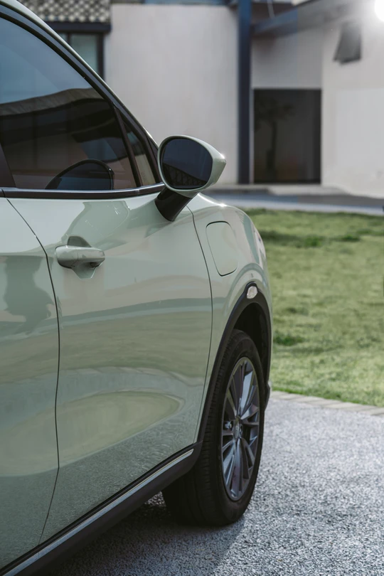 停在现代房屋前的绿色汽车的照片