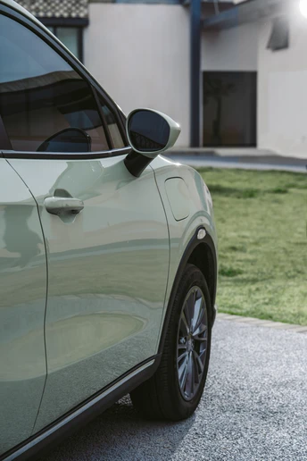 停在现代房屋前的绿色汽车的照片