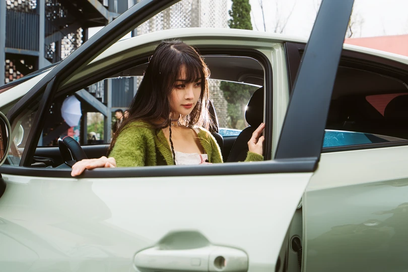 一位女性坐在汽车里看着她的手机