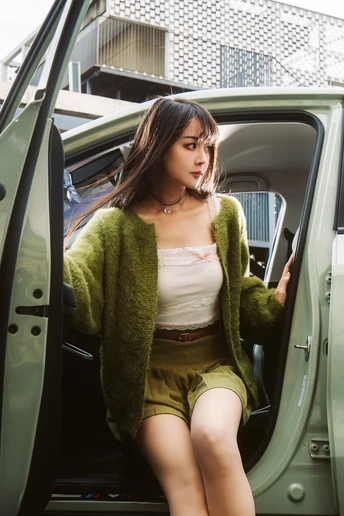 一个年轻女子坐在绿色汽车内部