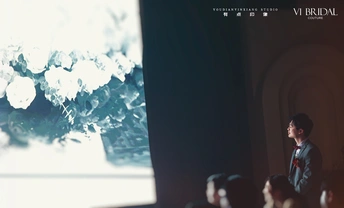 一个人站在一个房间的大窗户前 周围有很多人群。