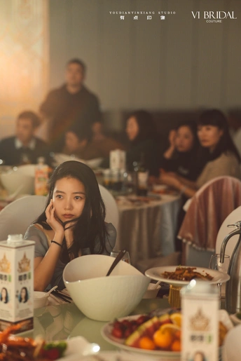 一个年轻女孩在餐厅与别人一起坐在桌子旁用餐。