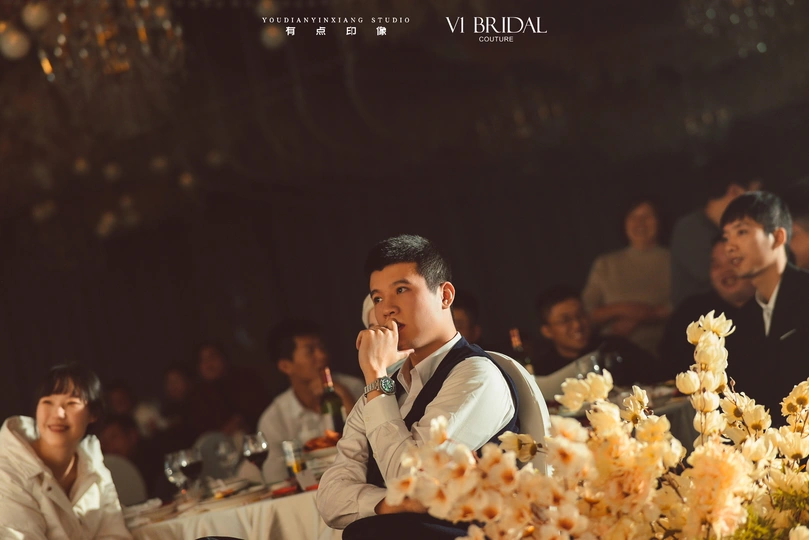 一个坐在桌子前的男人 桌子上有花。