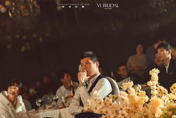 一个坐在桌子前的男人 桌子上有花。