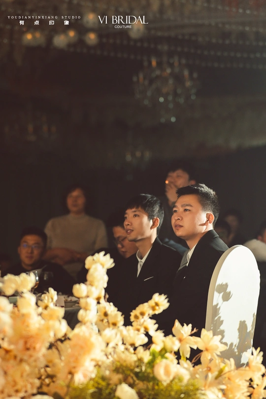 一些人站在一张桌子周围 桌子上放着花。