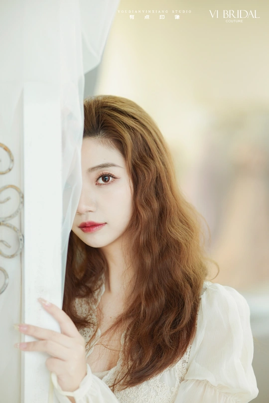 一位年轻女子凝视着窗外挂着白色窗帘的窗户的肖像