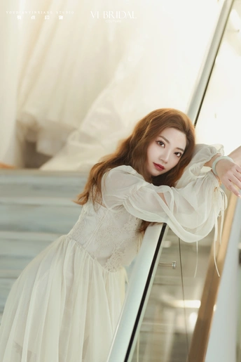 一个美丽的年轻女子穿着白色连衣裙站在楼梯上