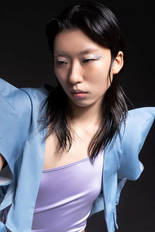 一位穿着蓝色衬衫的年轻女子在黑色背景上摆姿势