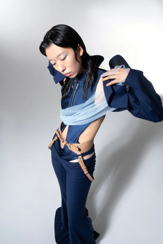 一位年轻的女模特穿着蓝色服装在白色背景上摆姿势