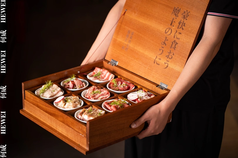 一个木托盘上放着一个装寿司的小盒子