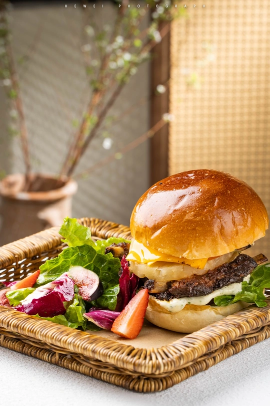 一只篮子放在桌子上 上面放着汉堡 面包片 生菜 番茄和其他蔬菜。