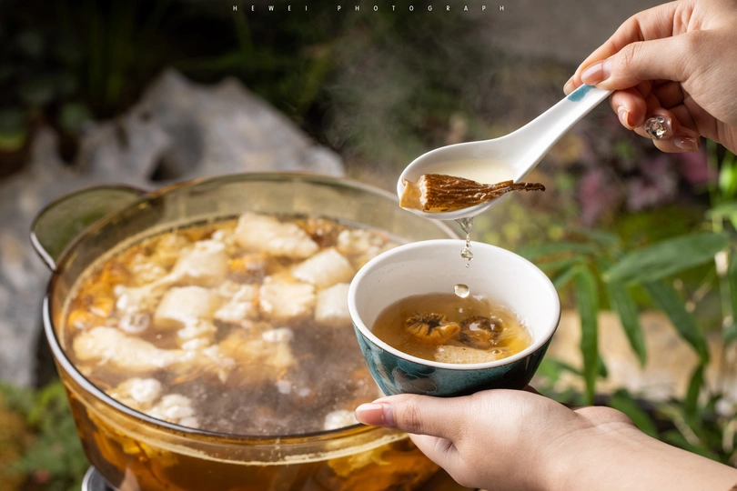 一个人拿着勺子 汤勺上盛着汤 正对着锅里的食物