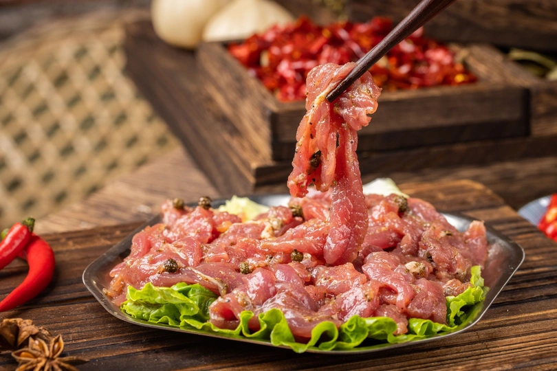 盘子上放着筷子 上面有肉、生菜、蔬菜和香料 放在木桌上。