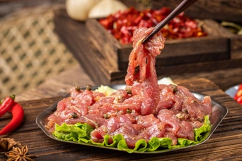 盘子上放着筷子 上面有肉、生菜、蔬菜和香料 放在木桌上。