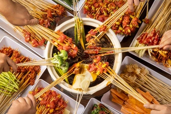 盘子上有食物和用筷子夹着食物的人们