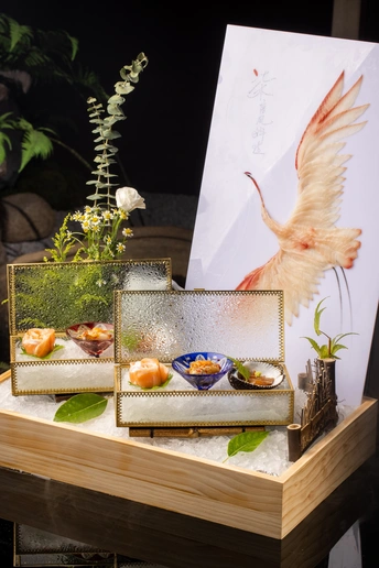 一个木制桌子 配有一个小托盘食物和寿司盘