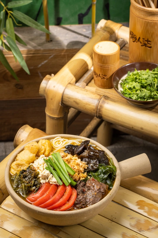 一碗装满面条、肉和蔬菜的碗 放在木椅上