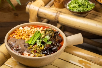 木桌上的汤碗 里面有蔬菜和玉米