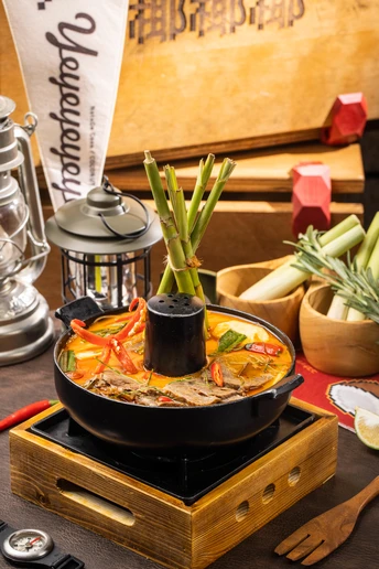 一个木制桌子顶部放着一锅食物和一个碗蔬菜。