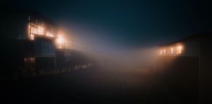 夜晚的黑暗街道 有火车在雾中 建筑物上有灯光。