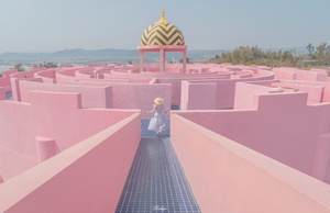 一个坐在粉色建筑迷宫边缘的女人