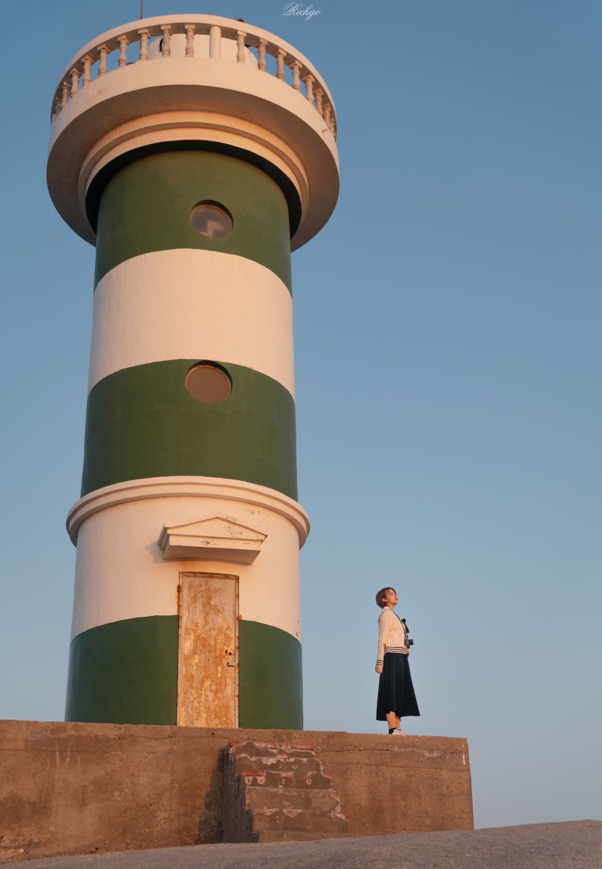 一位男子和一位女士站在一盏绿色和白色的灯塔前