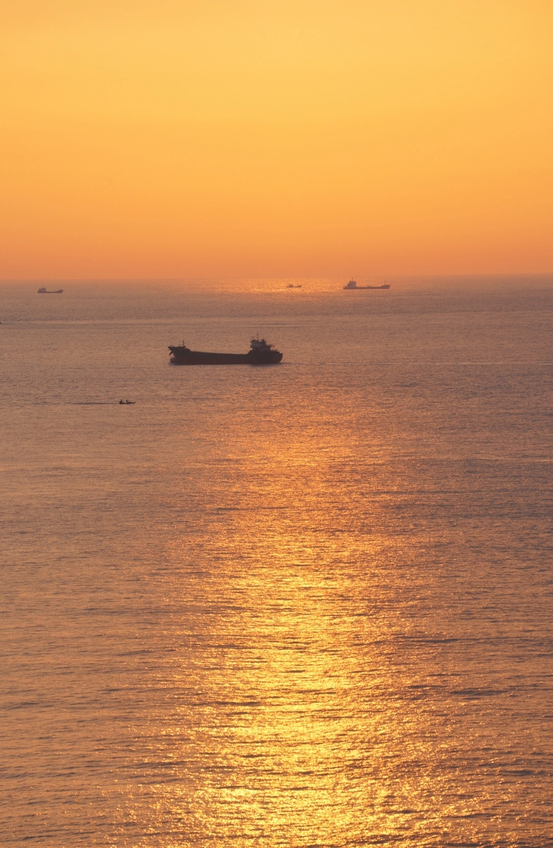 夕阳下的大型水域 夕阳在地平线上落下 一艘船在水中漂浮。