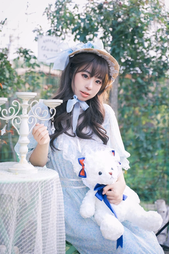 一位穿着蓝色连衣裙的年轻女子抱着一只白色泰迪熊