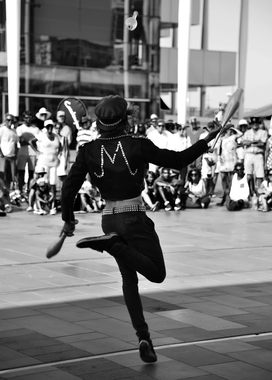 一个人在人群前表演舞蹈 人群中有撑着伞的人。