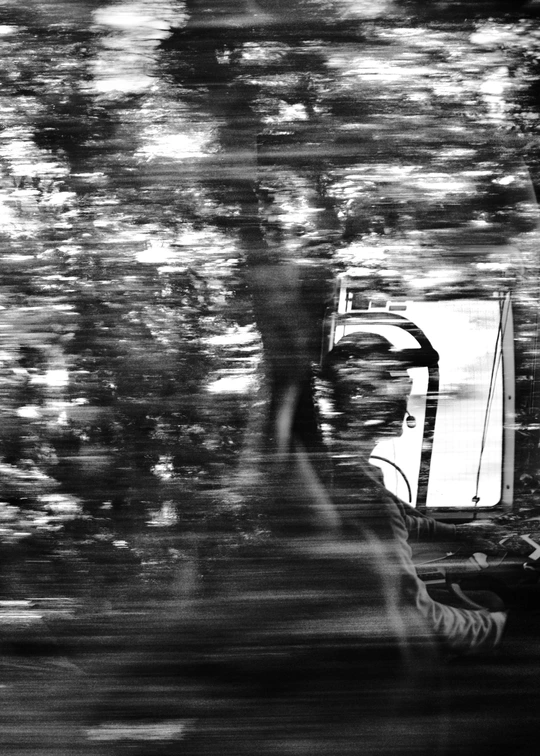 一个人在公路上驾驶一辆汽车 周围有树木和一辆卡车 一张黑白照片