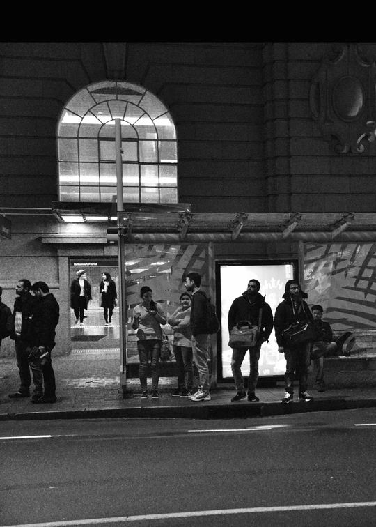 一张黑白照片 夜晚 人们站在公交车站