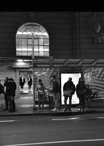 一张黑白照片 夜晚 人们站在公交车站