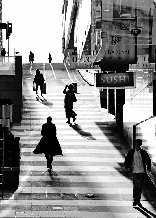 一张黑白照片 人们正在街道上带着行李走。